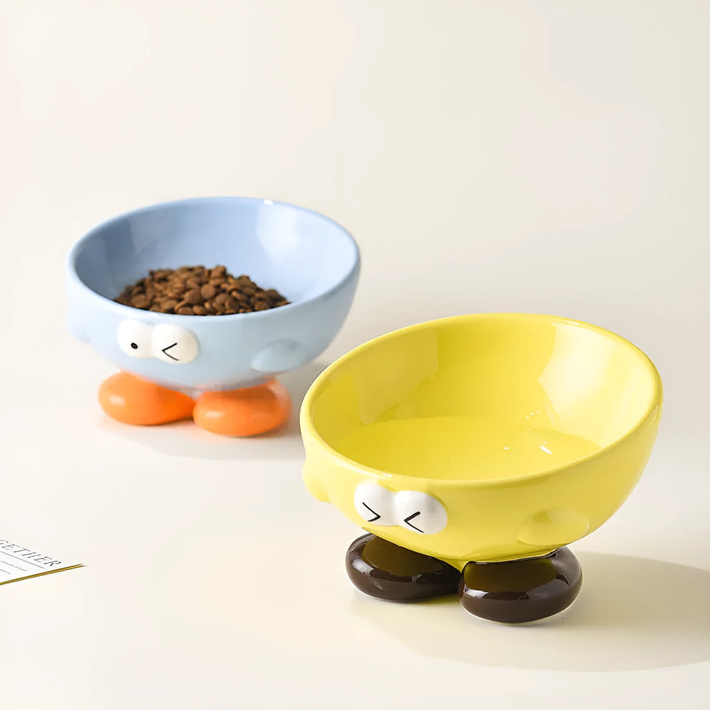 Ceramic slanted pet bowl with cute expression design in blue, yellow, and set colours for cervical spine support.