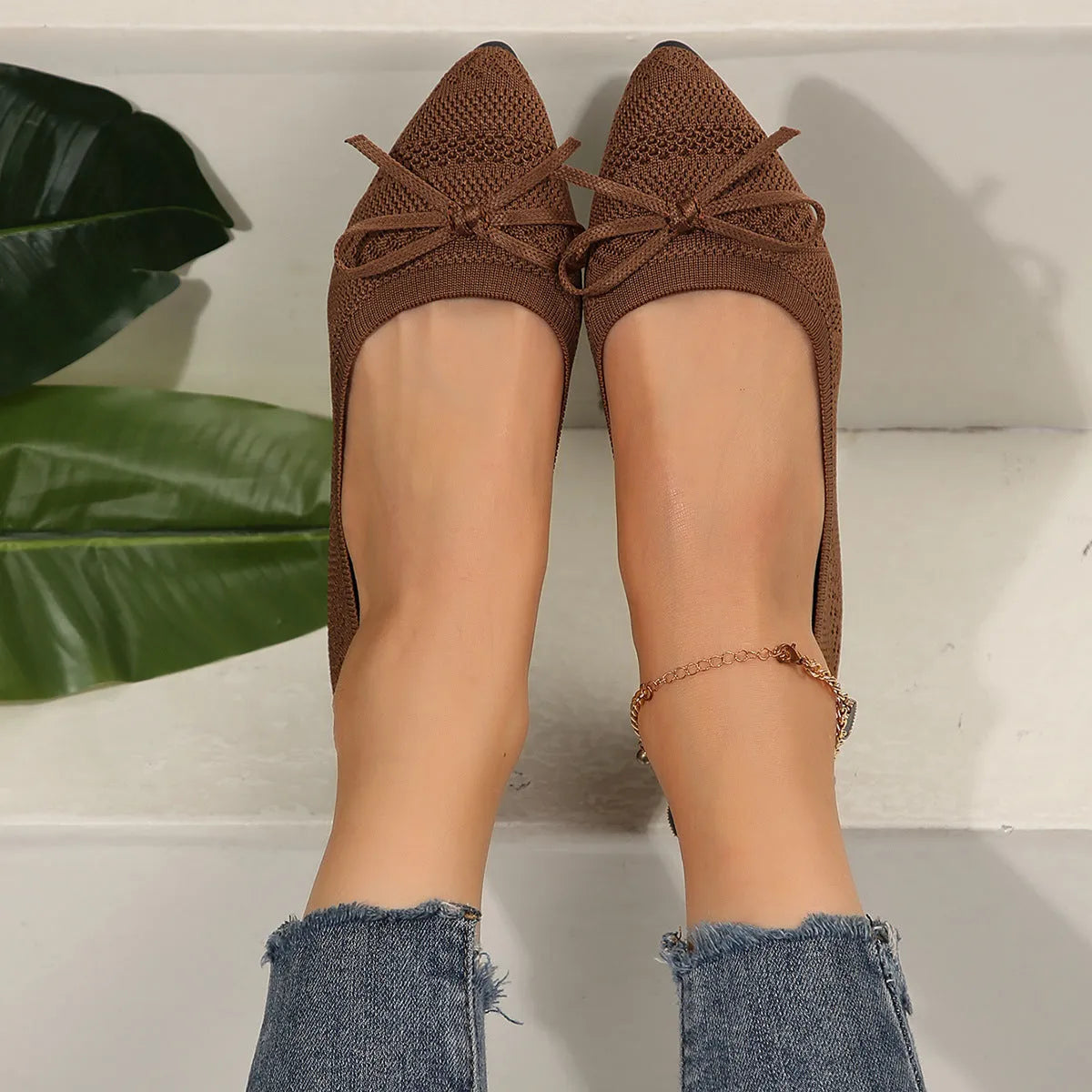 Women's blue knitted loafers with a bow detail and pointed toe on a flat rubber sole.