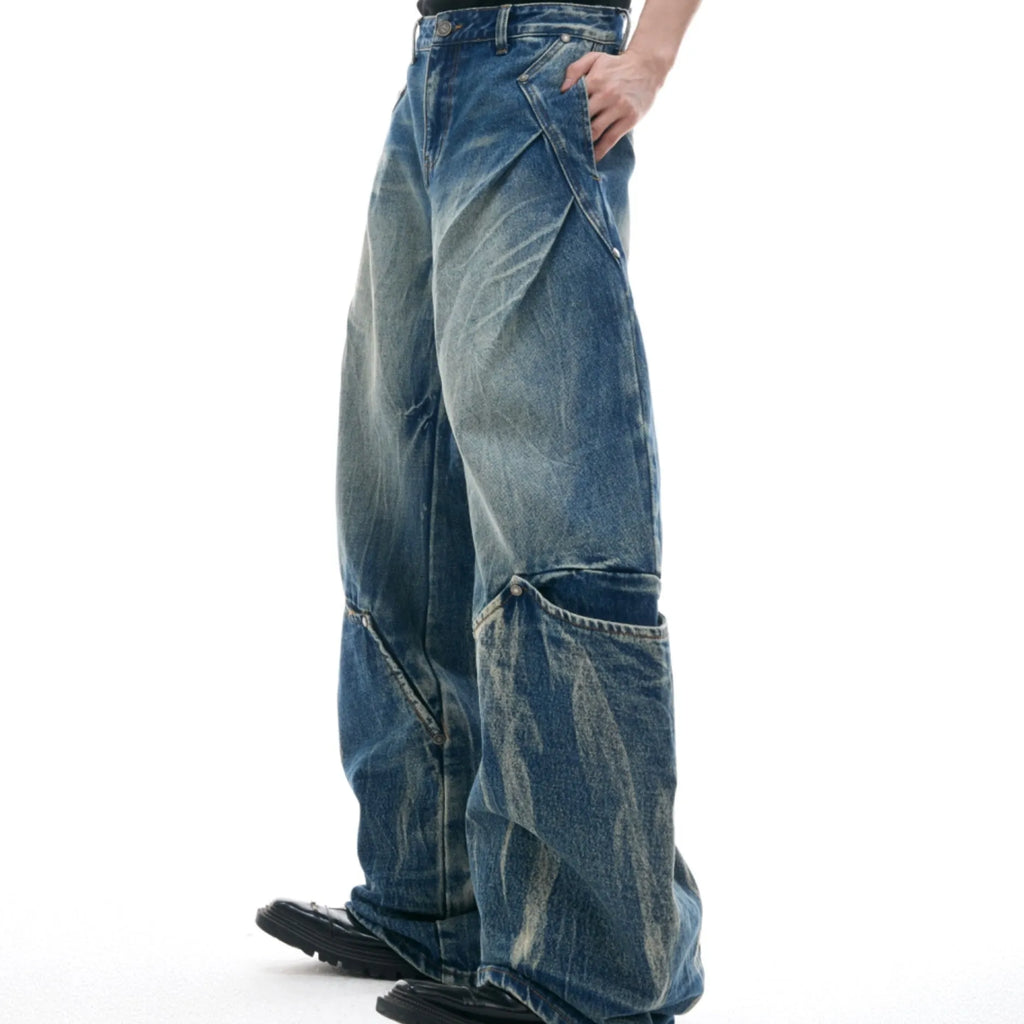 Man wearing verdant blue loose-fit jeans with a burst pattern wash and curved knife cut, front and side view.