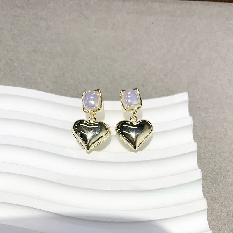 Small gold heart stud earrings with hypoallergenic metal finish on white background