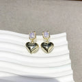 Small gold heart stud earrings with hypoallergenic metal finish on white background