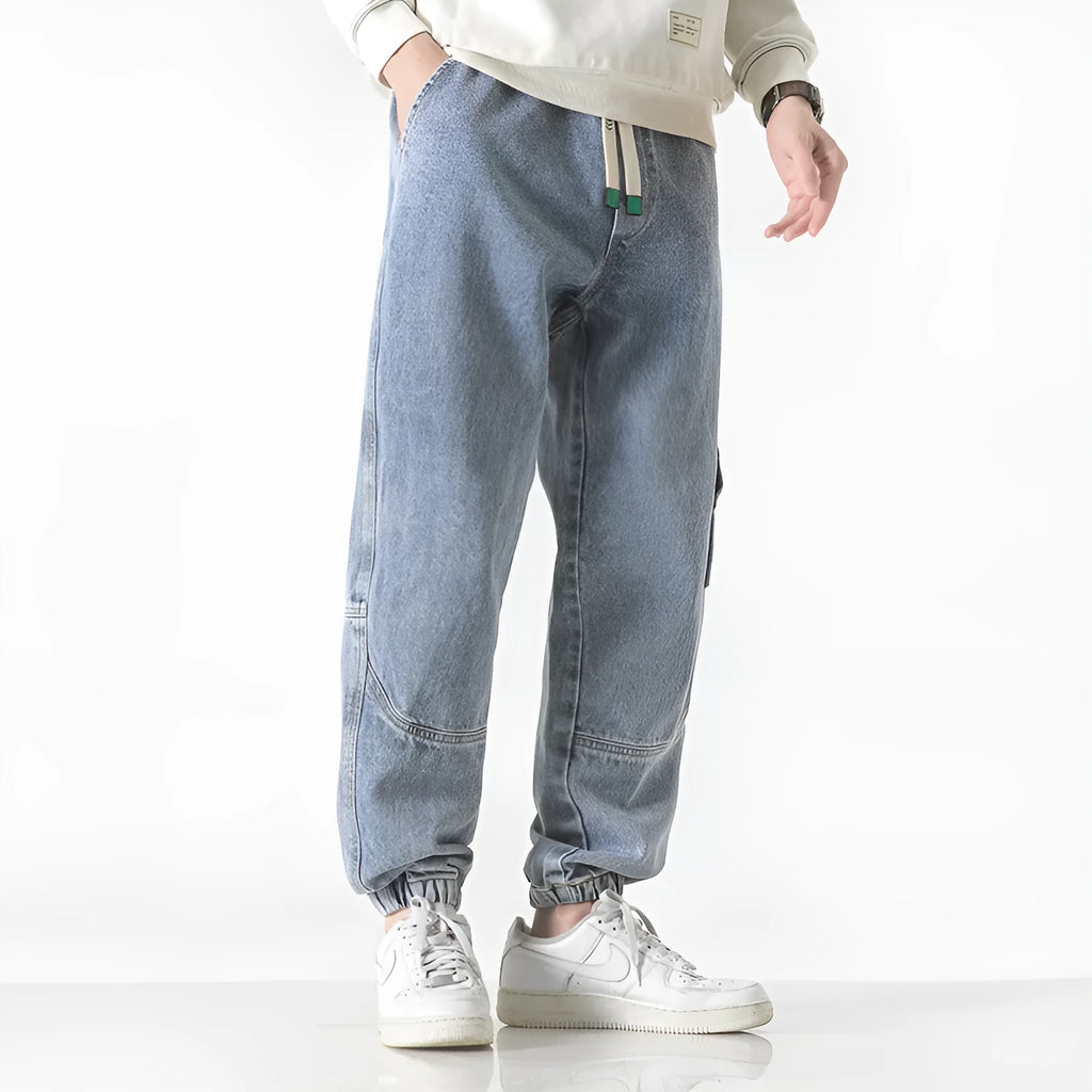 Men's loose-fit tapered cotton trousers in grey, shown laid flat, highlighting the tapered leg silhouette.