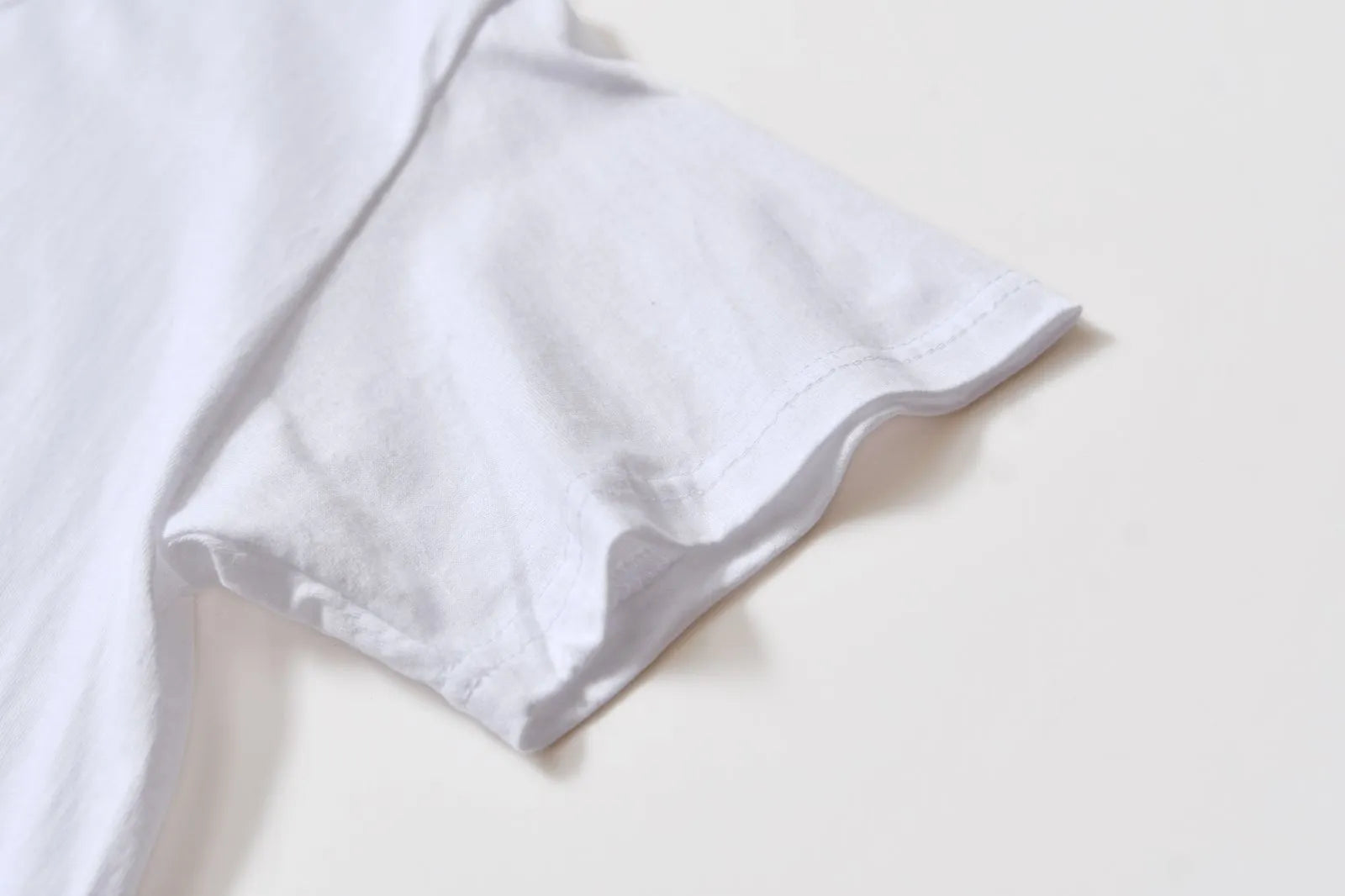White cotton pullover overalls with short sleeves and a round neck, shown on a hanger.