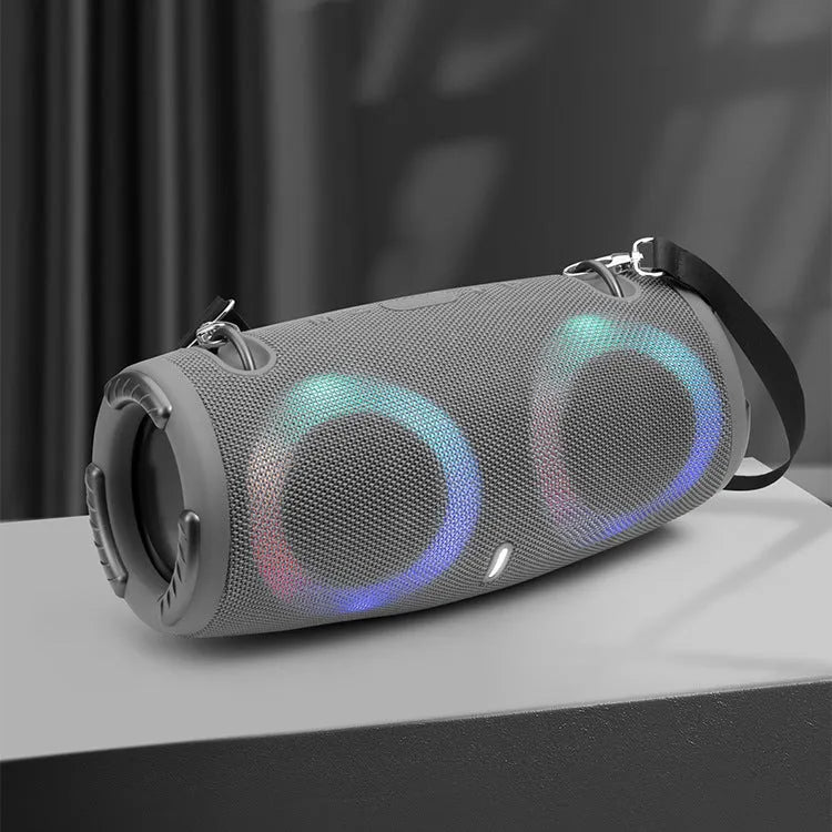 War Drum portable Bluetooth speaker with glowing RGB light ring in camouflage colour, sitting on grass.