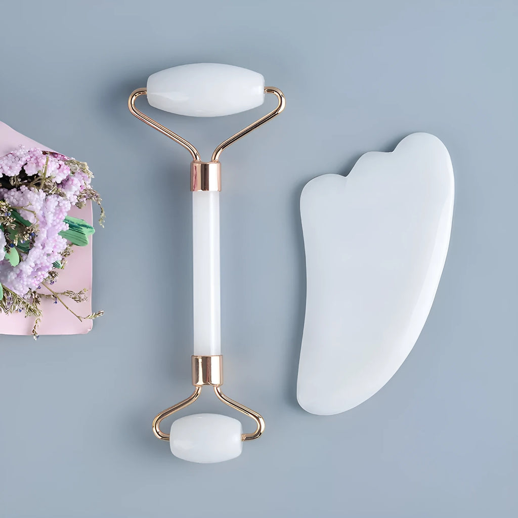 White jade double-headed facial roller and gua sha board set on a plain background.
