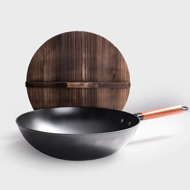 Traditional black iron wok with a long wooden handle on a kitchen counter.