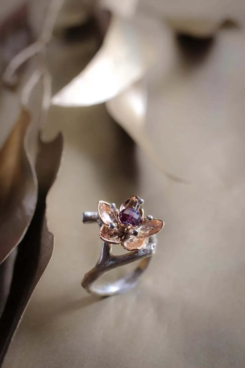 Geometric silver alloy ring with floral design and two-tone finish on a plain background