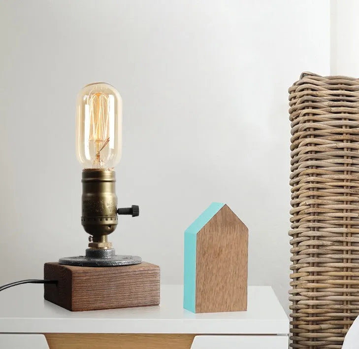 Small wooden and iron water pipe style table lamp on a surface.