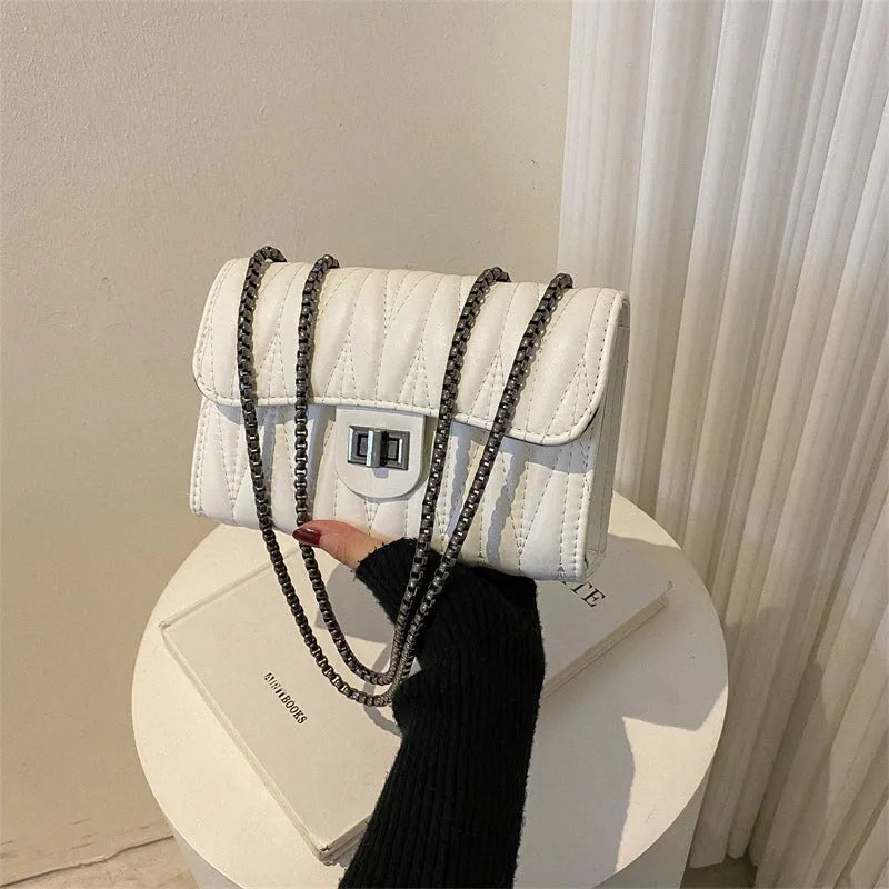 Small beige women's crossbody bag with a retro diamond texture pattern and a soft carry handle.