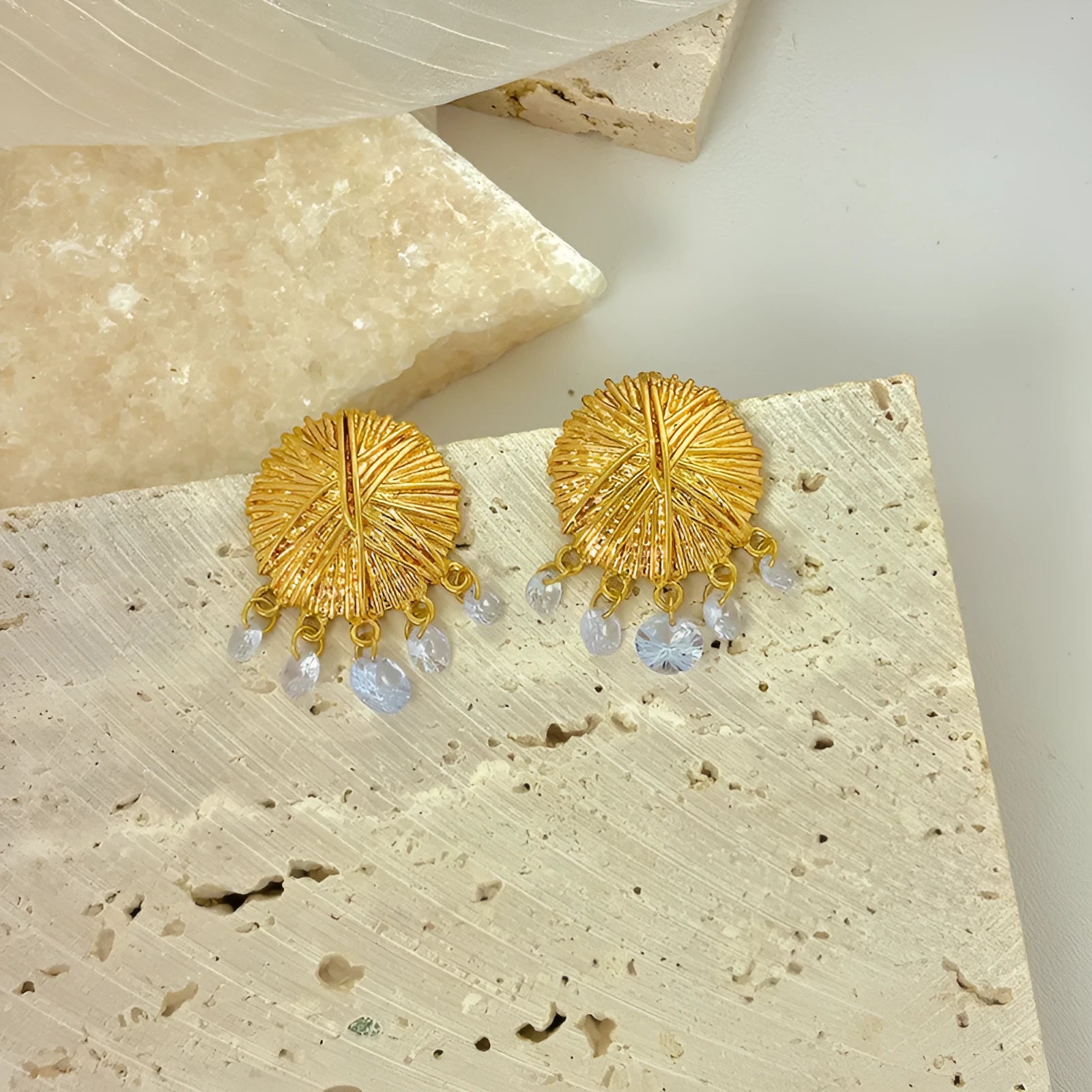 A pair of circular gold geometric hoop earrings on a plain background