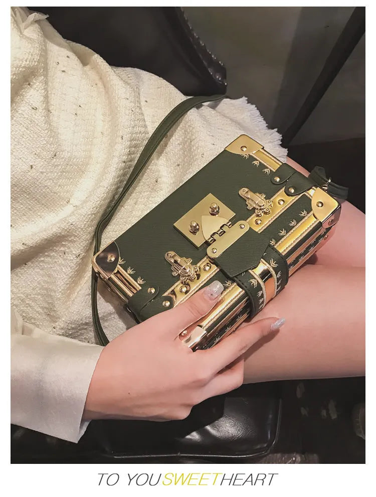 Hard-sided black women's shoulder bag with a flap closure, adjustable strap, and decorative metal rivets.