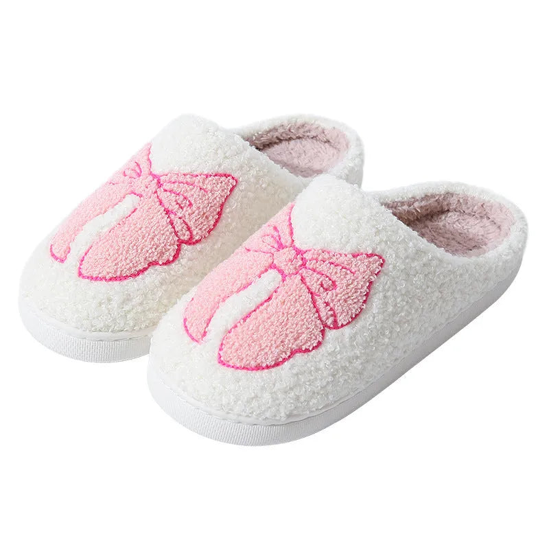 A pair of pink cartoon bow knot suede slippers with a TPR sole, shown from the side.