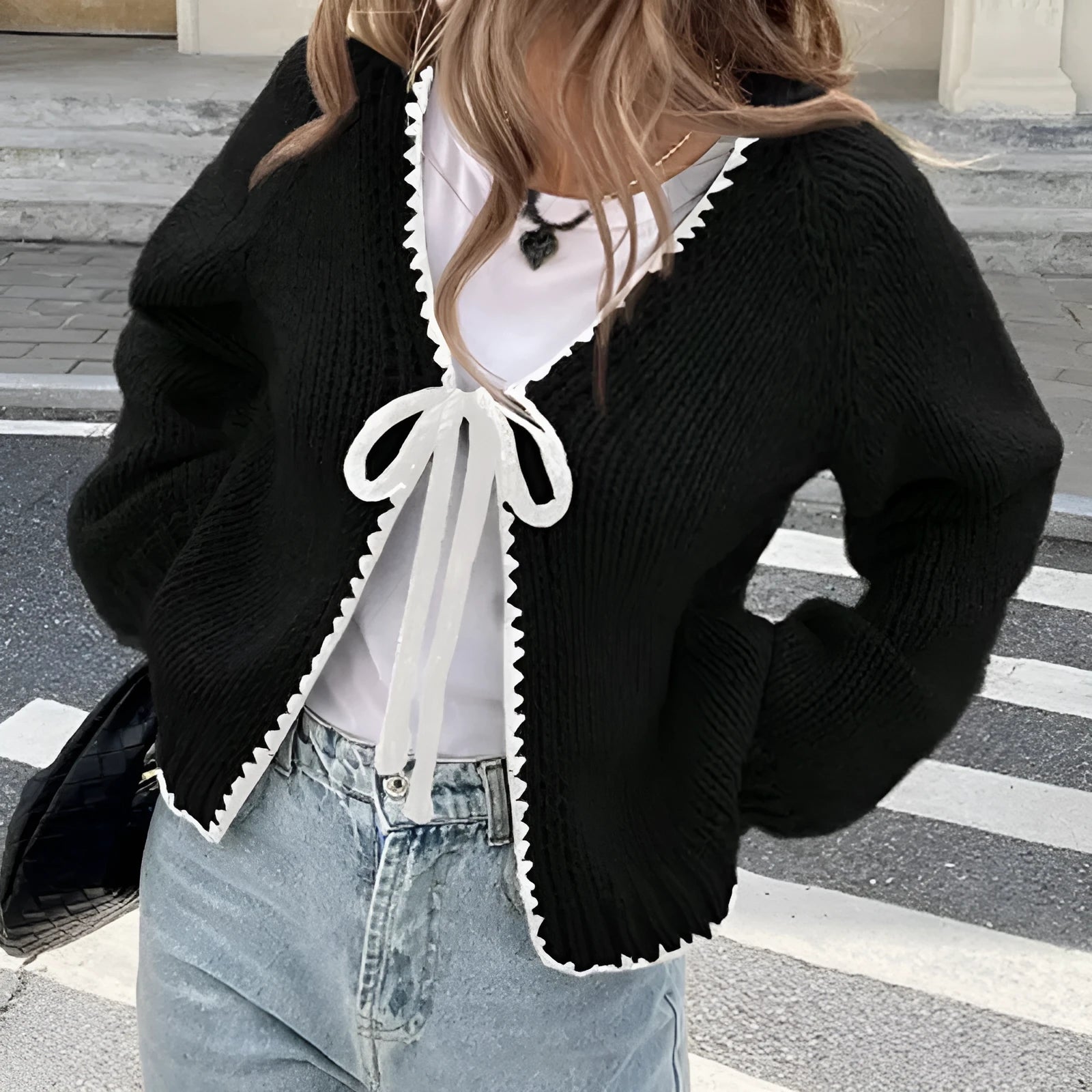 A solid colour loose-fit cardigan with long sleeves and small crochet flower details on the front.