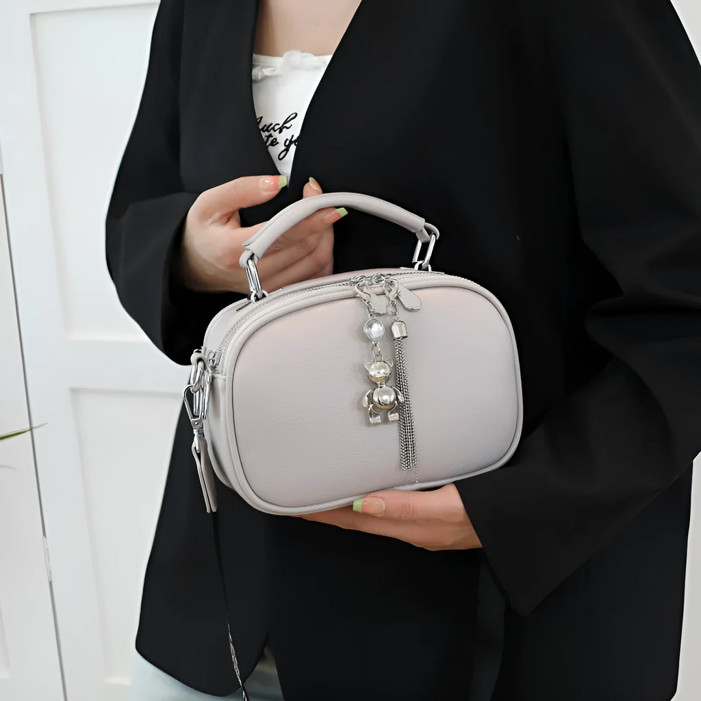 Oval-shaped women's small square bag in soft PU leather with double strap, shown in multiple colours.