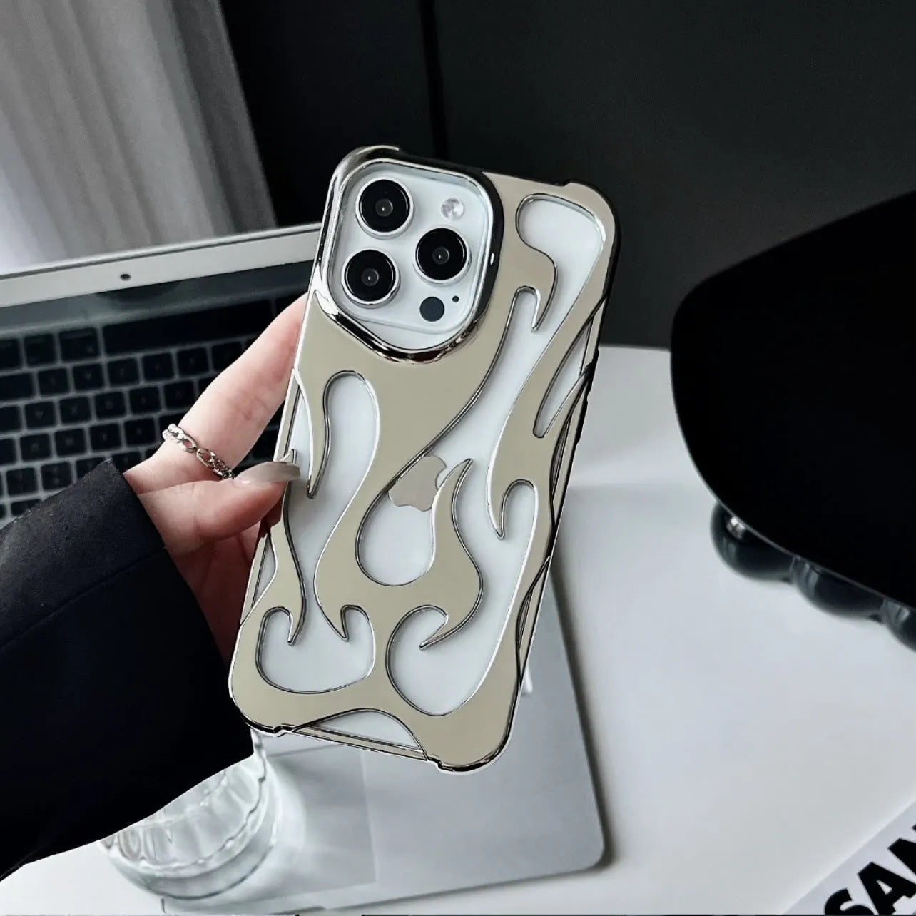 Electroplated hollow flame pattern mobile phone case for iPhone on a dark background, showing silver metallic finish.