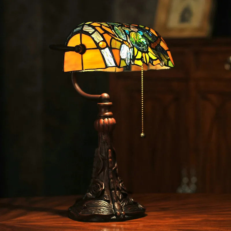 Tiffany-style desk lamp with a coloured stained glass shade on a resin base.
