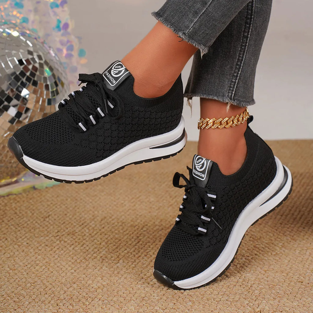 Women's black and white lace-up mesh platform sneakers with a flat rubber sole on a neutral background.
