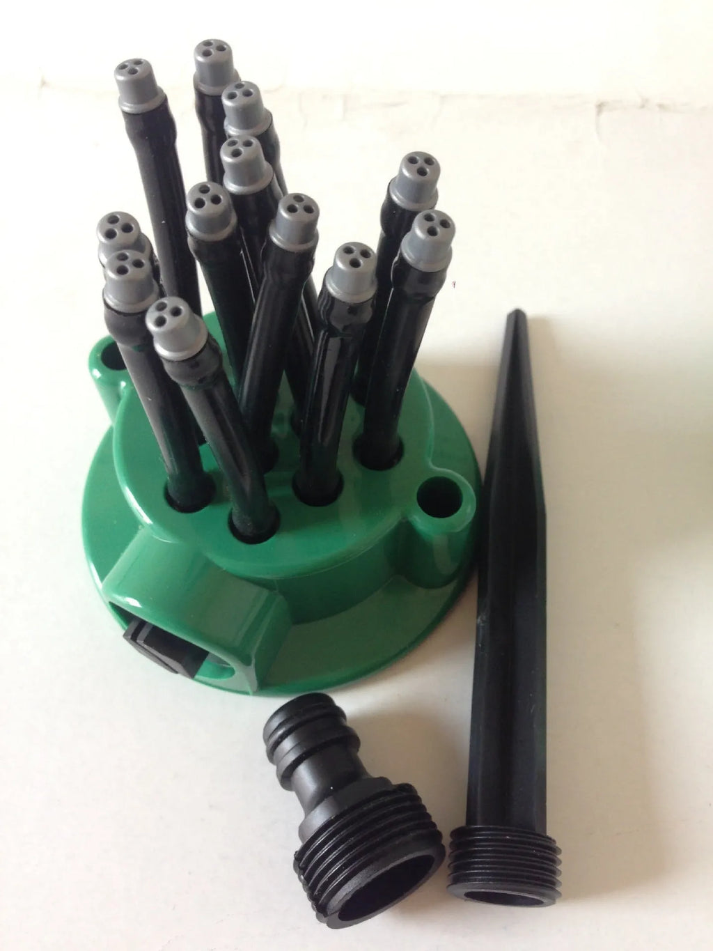 Green plastic adjustable lawn sprinkler with flexible spray noodles on 9cm base