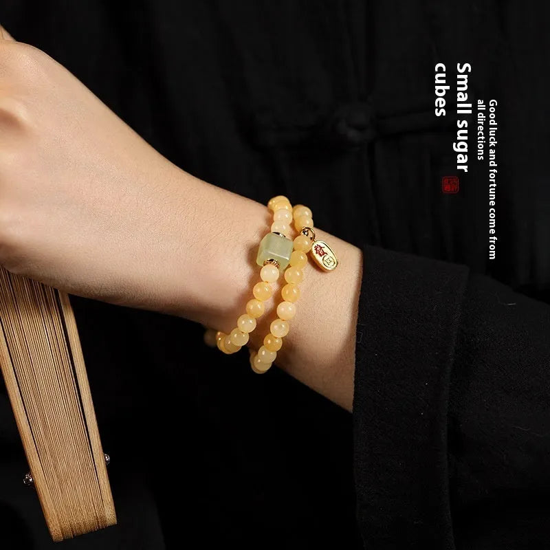 Women's hand-woven topaz bracelet with mantra barrel beads, square sugar beads, and fu charm in yellow jade