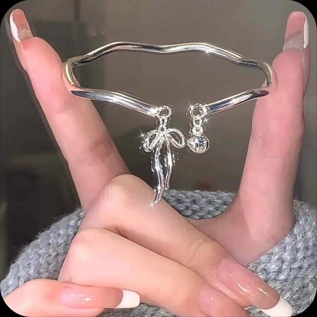 Silver tone adjustable bracelet with a 3D bow charm and magnetic clasp on a wrist.