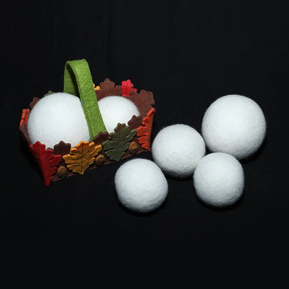Set of wool laundry drying balls next to cotton storage bag for tumble dryers