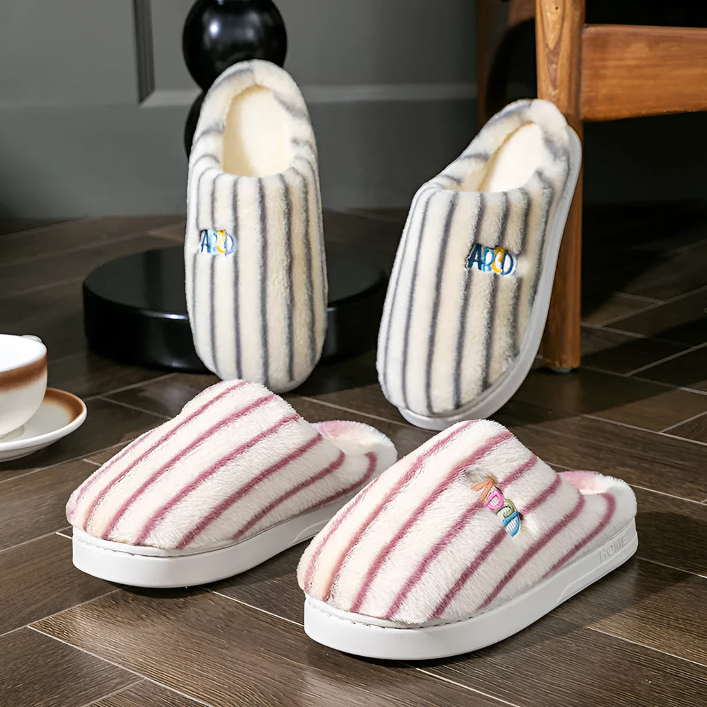 A pair of colourful vertically striped cotton flip flop slippers for adults on a plain background.