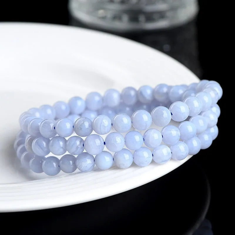 Close-up of a blue striped agate beaded bracelet with Ruyi design on a neutral background.