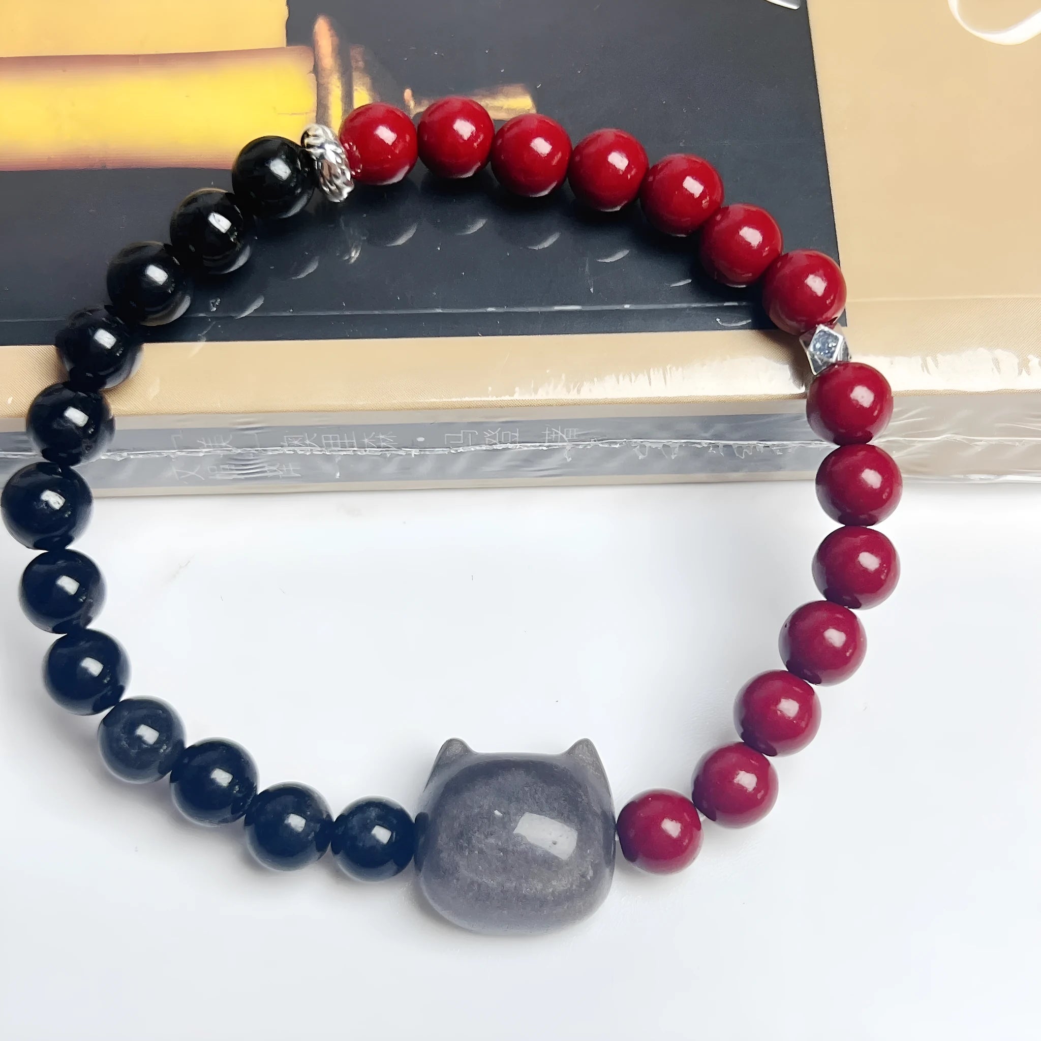 Obsidian-coloured cat charm on a colourful elastic bracelet strap.
