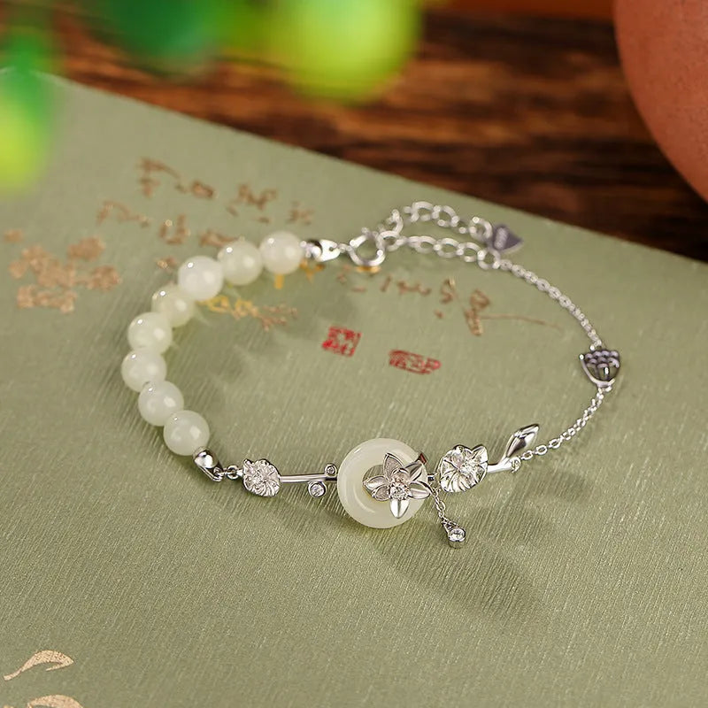 Women's 925 silver bracelet with inlaid Hetian jade centrepiece and ornate lotus peace buckle design.
