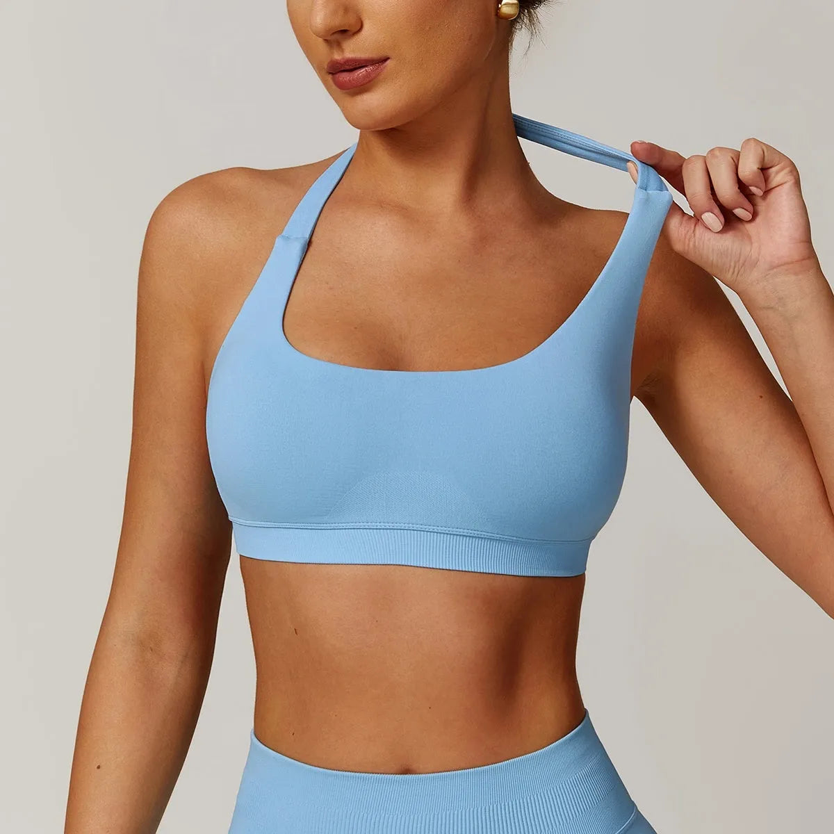 Women's halter neck yoga sports bra in plum purple, shown from the front, showcasing the tie detail and medium support fit.