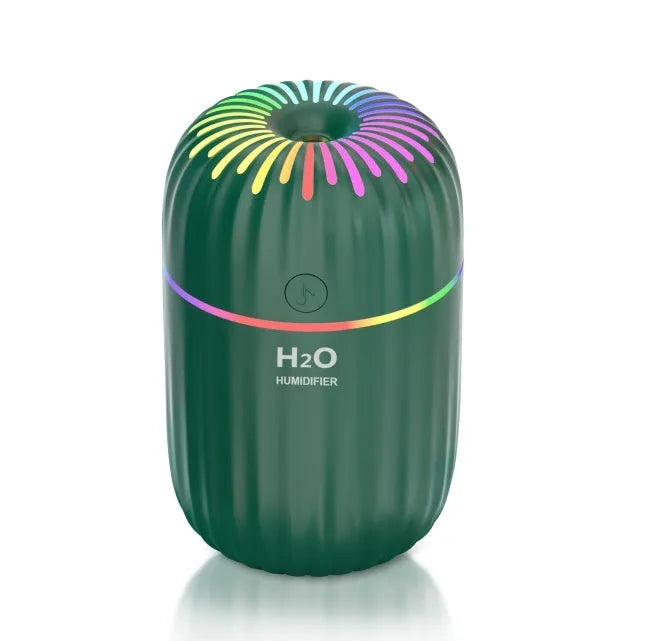 Compact white USB mini humidifier with water tank on a desk next to a laptop.