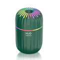Compact white USB mini humidifier with water tank on a desk next to a laptop.