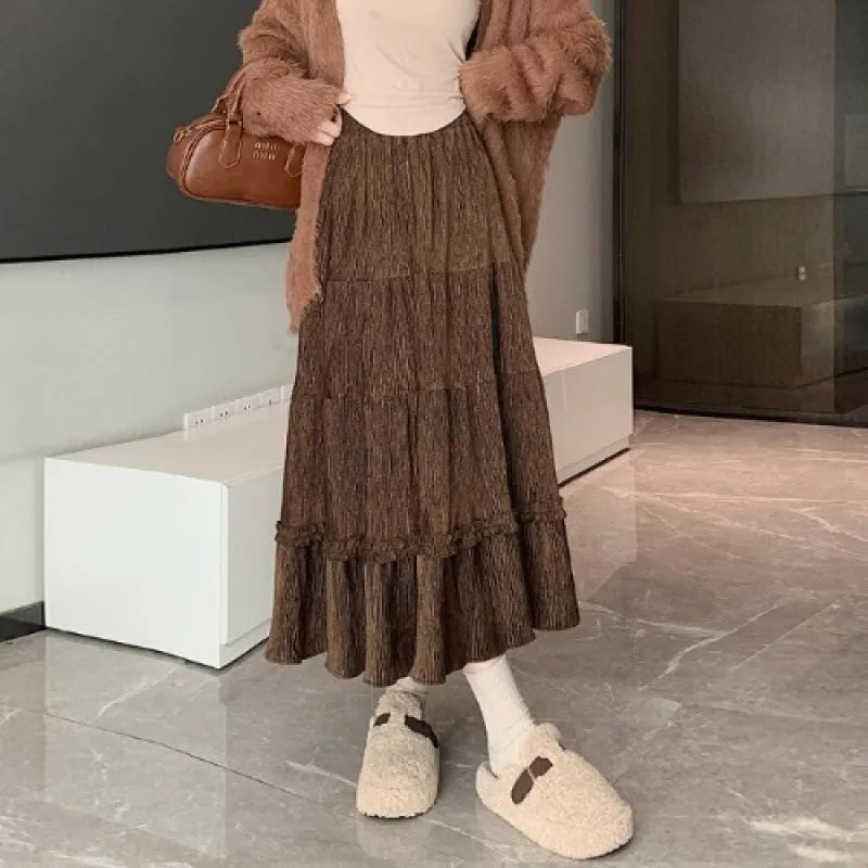 A woman wearing a beige corduroy A-line midi skirt with an elasticated waistband.