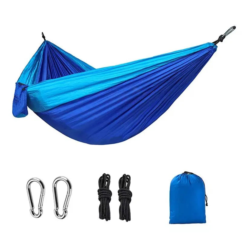 Blue parachute nylon camping hammock hung between two trees, showing its full 270cm length and 140cm width.