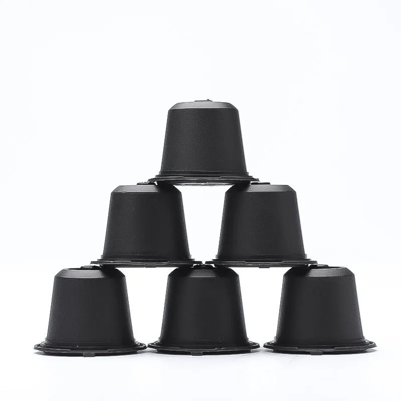 Set of six recyclable reusable plastic coffee filter cups in black, brown, and red with a spoon on wooden background