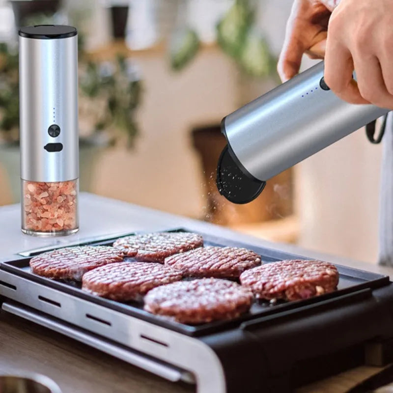 White electric salt and pepper grinder set with clear glass jar and stainless steel top on kitchen counter
