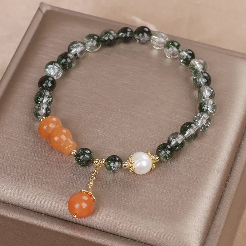 Green phantom quartz crystal bracelet with pearl and rhinestone accents on women's wrist