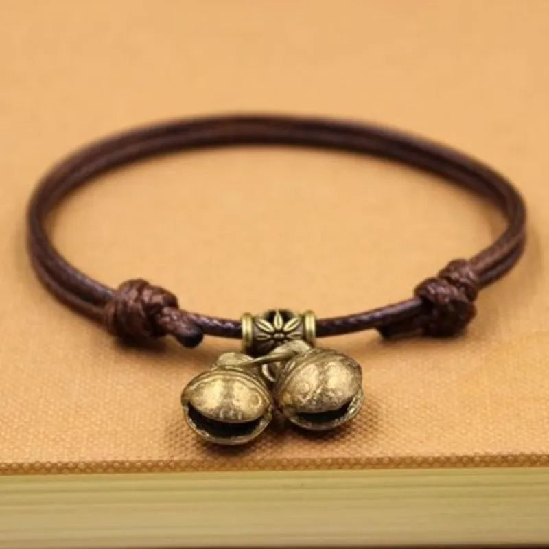 Close-up of an adjustable black nylon rope dog collar featuring a shiny brass bell.