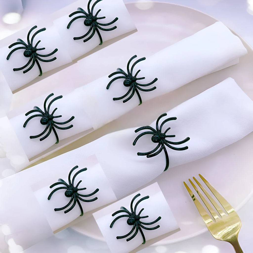 Six black alloy spider-shaped napkin rings on a dark table, showing detailed legs and a 5cm height.