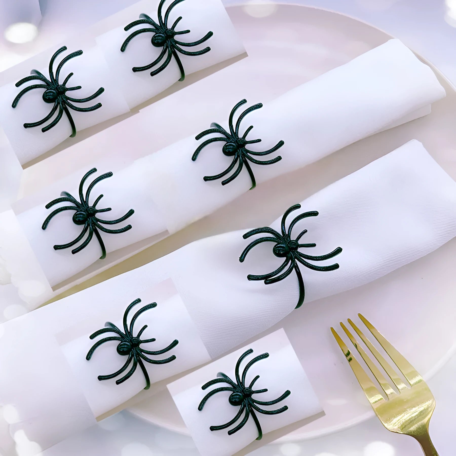 Six black alloy spider-shaped napkin rings on a dark table, showing detailed legs and a 5cm height.