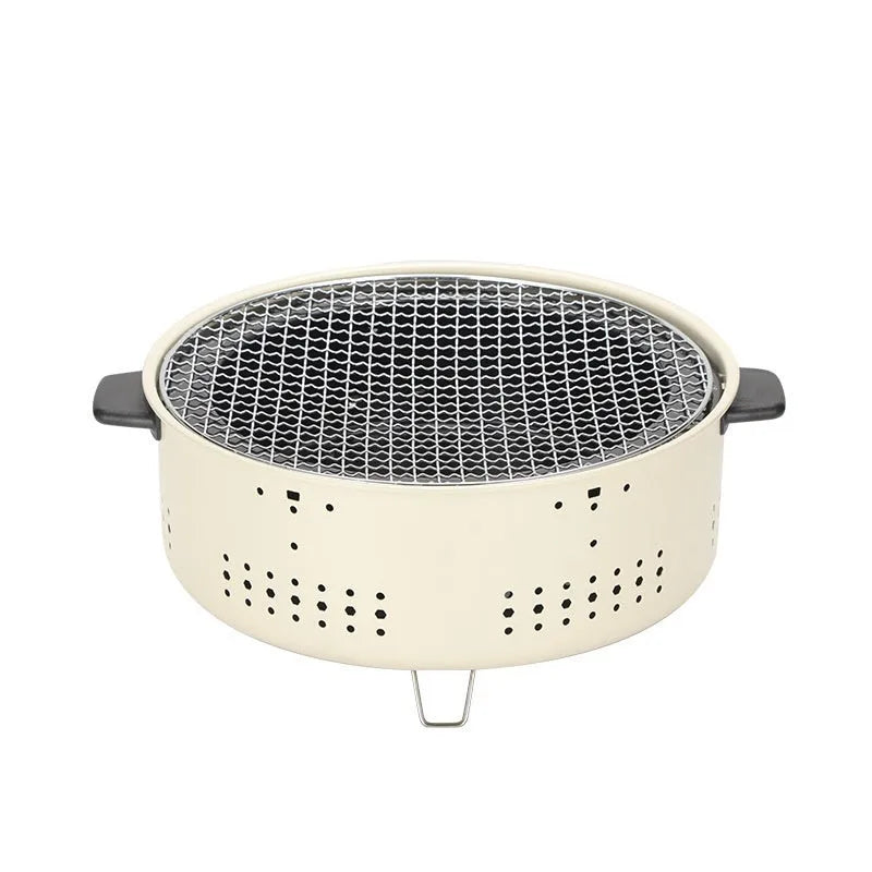 A white ceramic indoor charcoal stove with a cast iron grill rack on top, sitting on a wooden table.