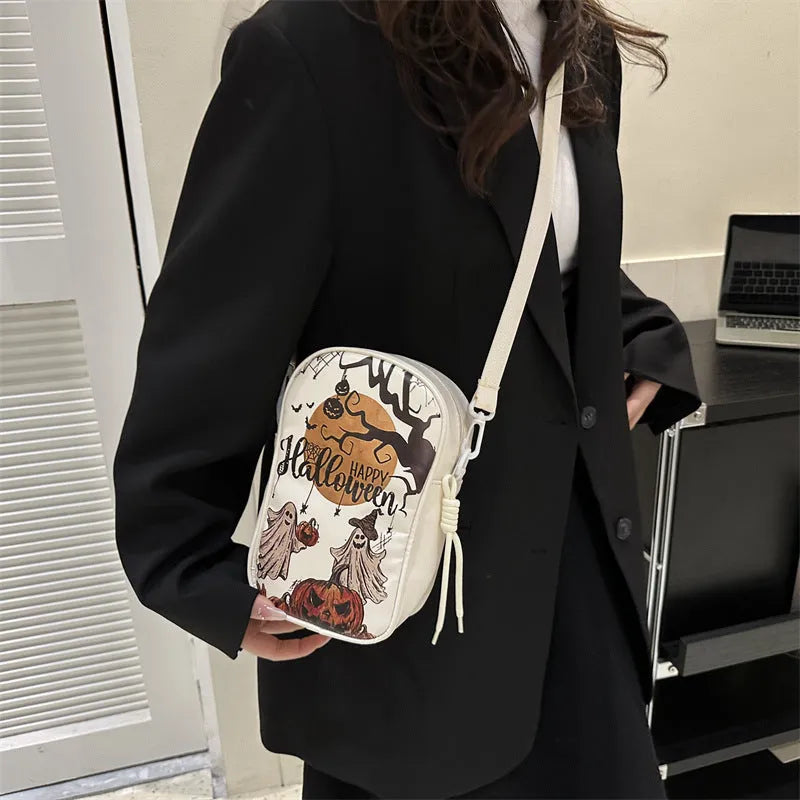 Black mini square crossbody bag with orange cartoon pumpkin, white ghost, and black bat graffiti print.