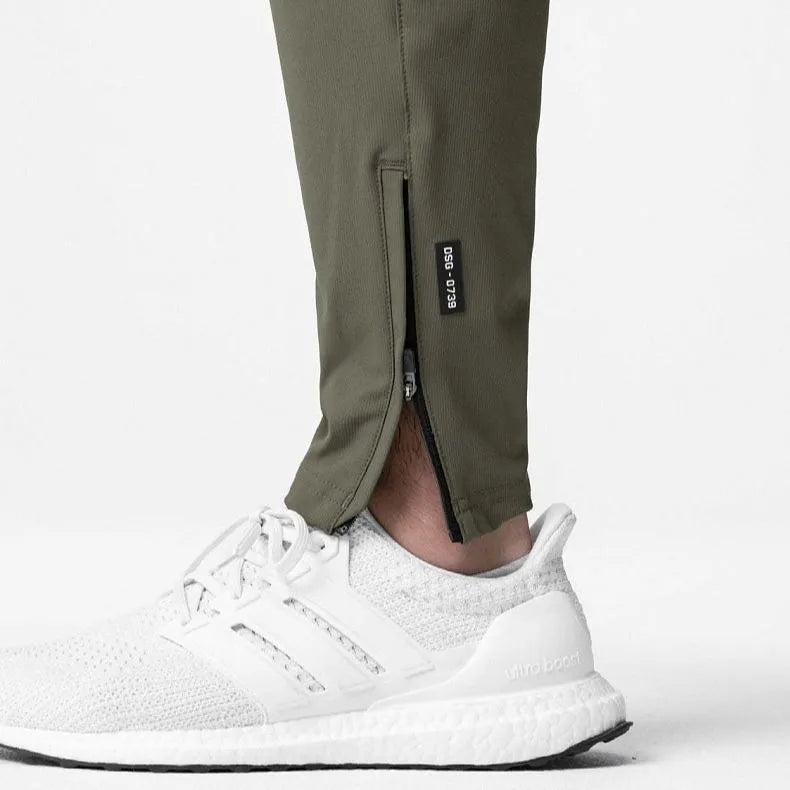 Men's grey loose-fit fitness trousers with ankle ties, made from quick-drying polyester fabric.