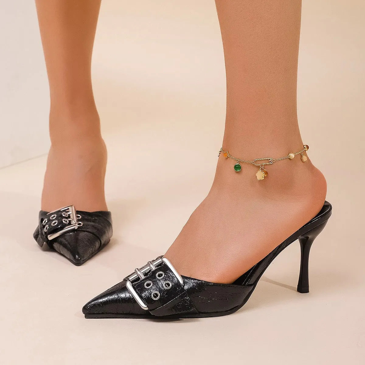 Black women's high heel shoes with pointed toe and buckle strap decoration.