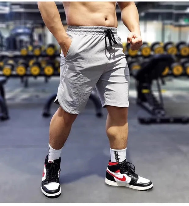 Men's thin quick-drying running shorts in black, blue, or grey on a hanger.