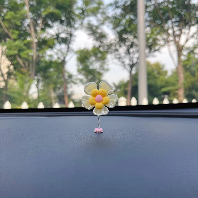 Small colourful plastic swing ornament for car dashboard, shown in multiple colour options.