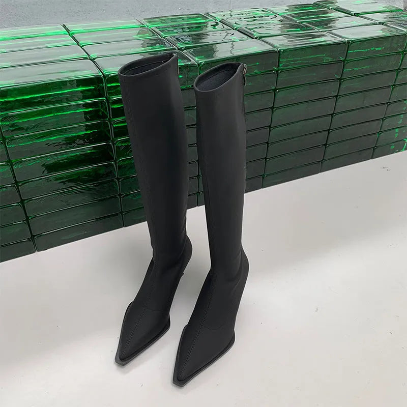 Black pointed-toe below-knee women's boots with a stiletto heel and a visible back zip on a neutral background.