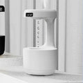 White columnar anti-gravity humidifier on a desk with LED clock display and visible mist.