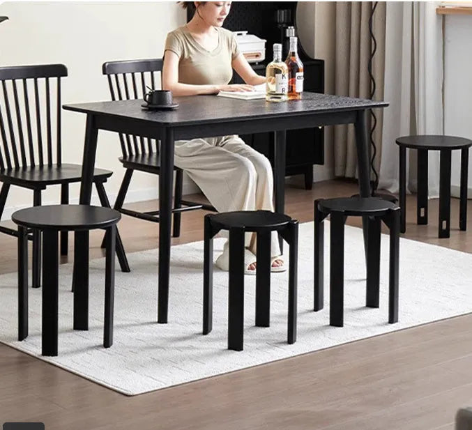 Set of four stackable iron dining stools with round seats in a modern design, shown in smoked black finish.