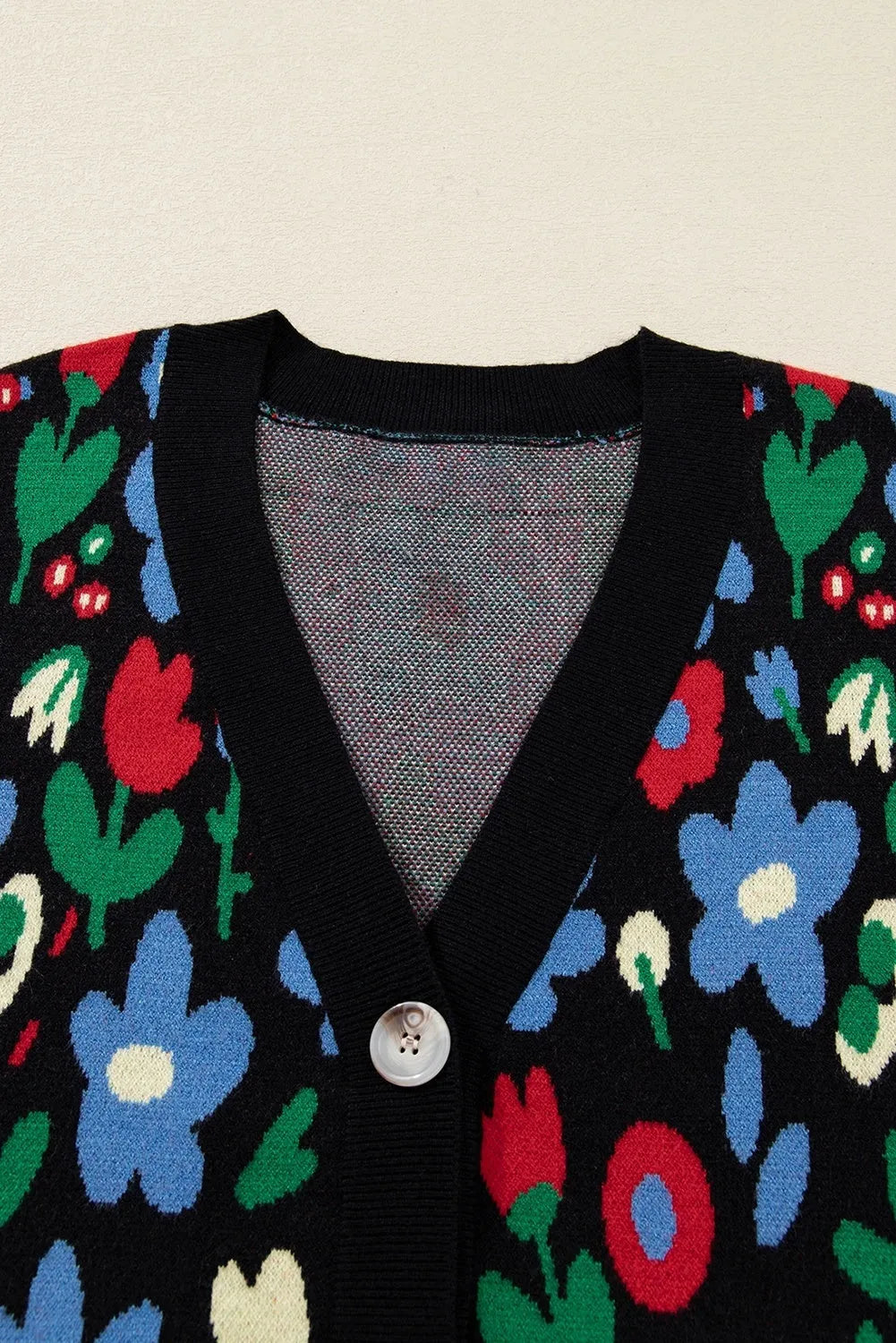 Black floral print V-neck button cardigan sweater with long sleeves and colour-block detail, laid flat